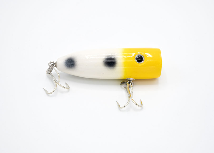 Side view of a yellow, white and black speckled pine wood fishing lure