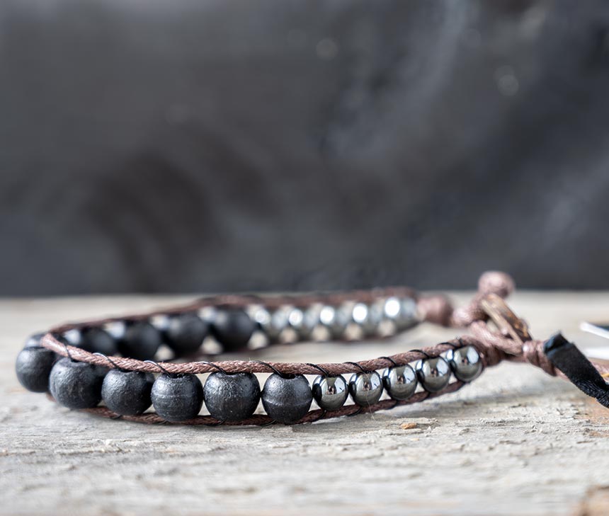 Side view of the Nomad Moonless Night men's bracelet by Lotus and Luna on a rustic wooden backdrop