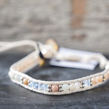 Front view of the women's Watermelon Wishes Moonstone bracelet by Lotus and Luna on a rustic wood backdrop