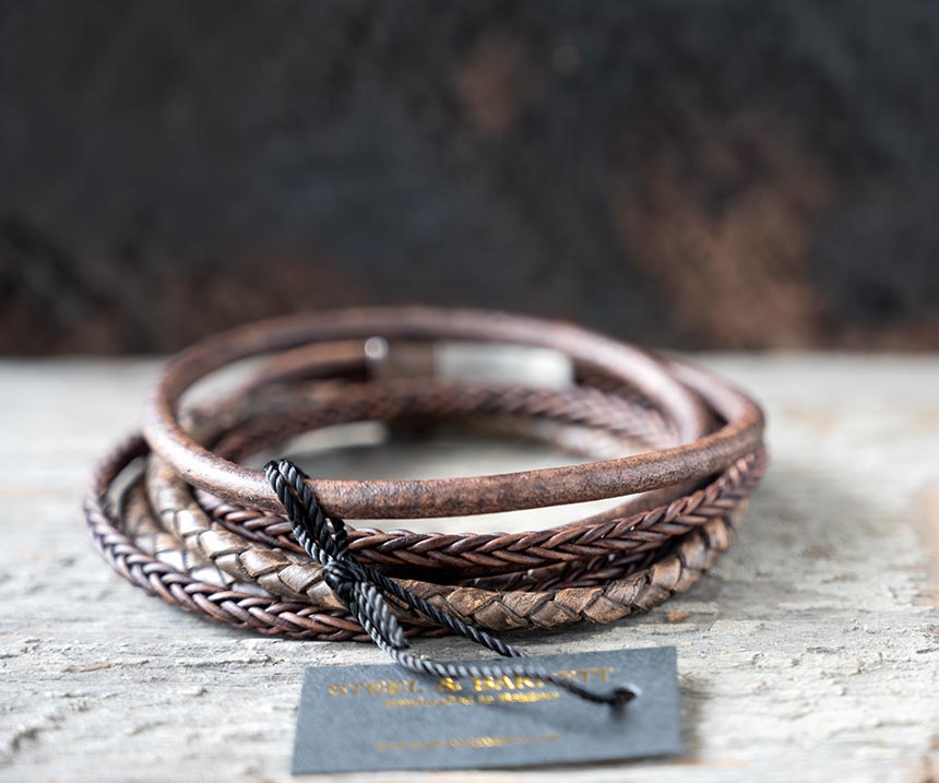Back view of the brown leather Bonacci bracelet by Steel & Barnett on a rustic piece of wood and backdrop