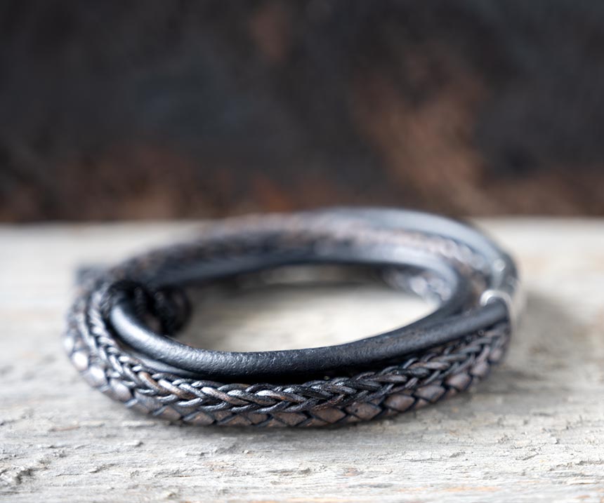 Right side view of the navy leather Bonacci bracelet by Steel & Barnett on a rustic piece of wood and backdrop