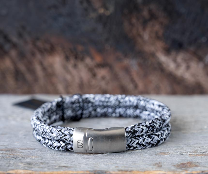 Front view of the Steel & Barnett Lake Rope Bracelet in black denim on a rustic piece of wood and wood backdrop