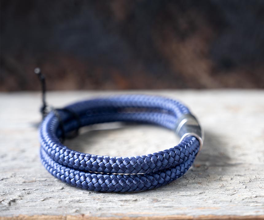 Right side view of the Steel & Barnett Lake Rope Bracelet in navy on a rustic piece of wood and wood backdrop