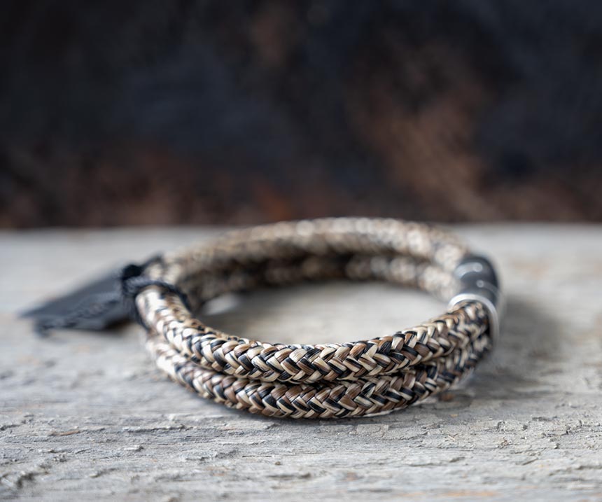 Right side view of the Steel & Barnett Lake Rope Bracelet in rusty on a rustic piece of wood and wood backdrop