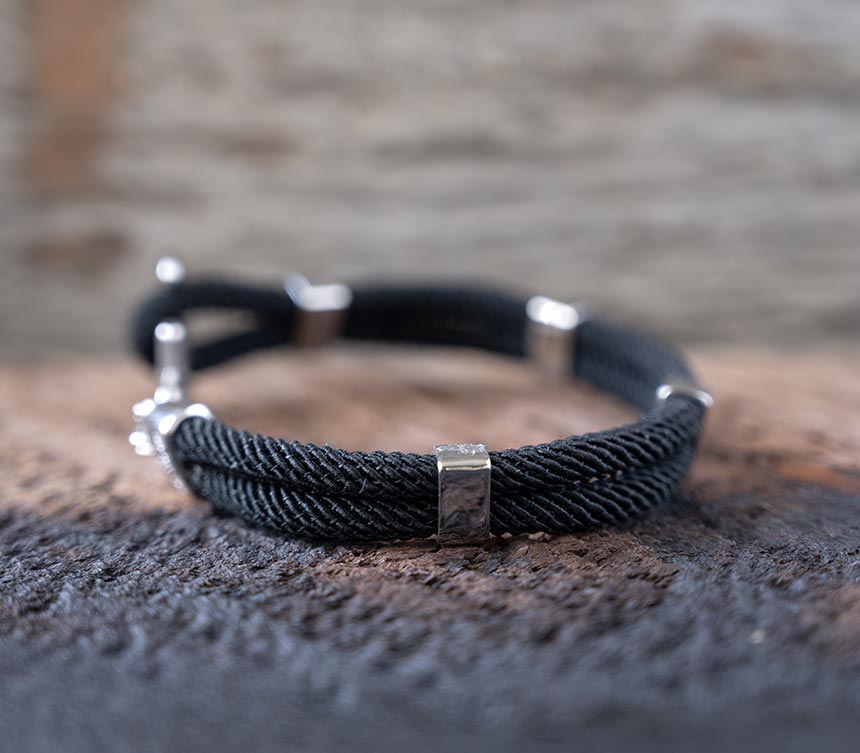 Left side view of the Women’s Maris Sal Nautical Anchored New Haven Bracelet in Black Bracelet on a Piece of Rustic Wood
