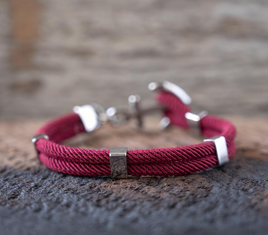 Back view of the Maris Sal Nautical Anchored New Haven bracelet in bordeaux resting on top of a piece of rustic wood