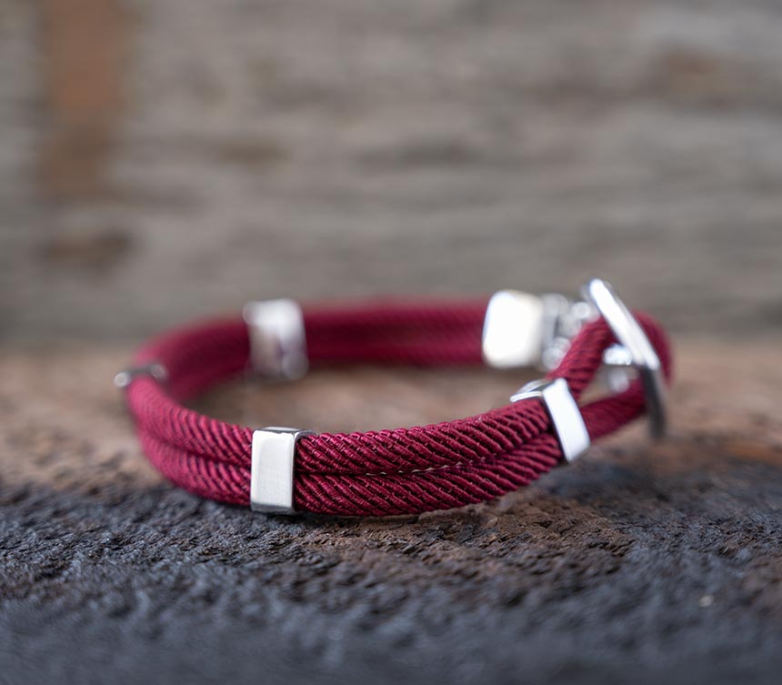 Right side view of the Women’s Maris Sal Nautical Anchored New Haven Bracelet in Bordeaux Bracelet on a Piece of Rustic Wood