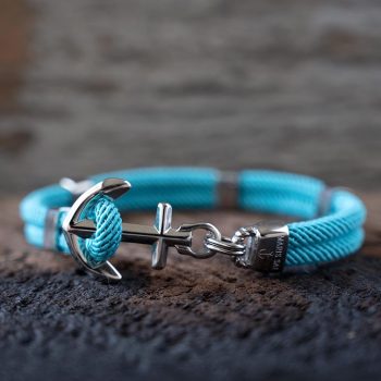 Front view of the Maris Sal Nautical Anchored New Haven bracelet in turquoise resting on top of a piece of rustic wood