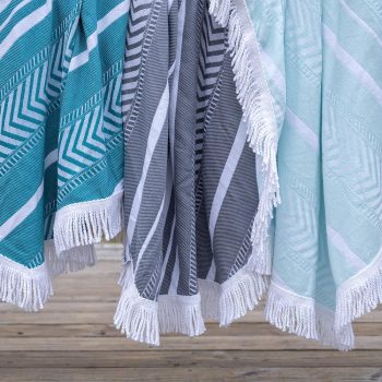 The Octavia Turkish towel set in teal, gray and mint by Case+Drift draped over a lake pier railing