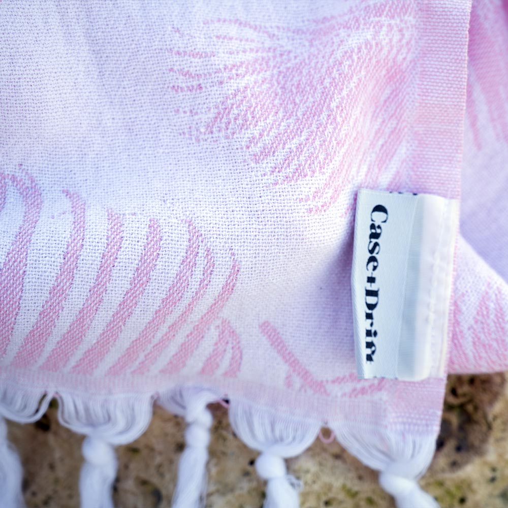 Closeup of the pink Palms Turkish towel by Case+Drift over a rock