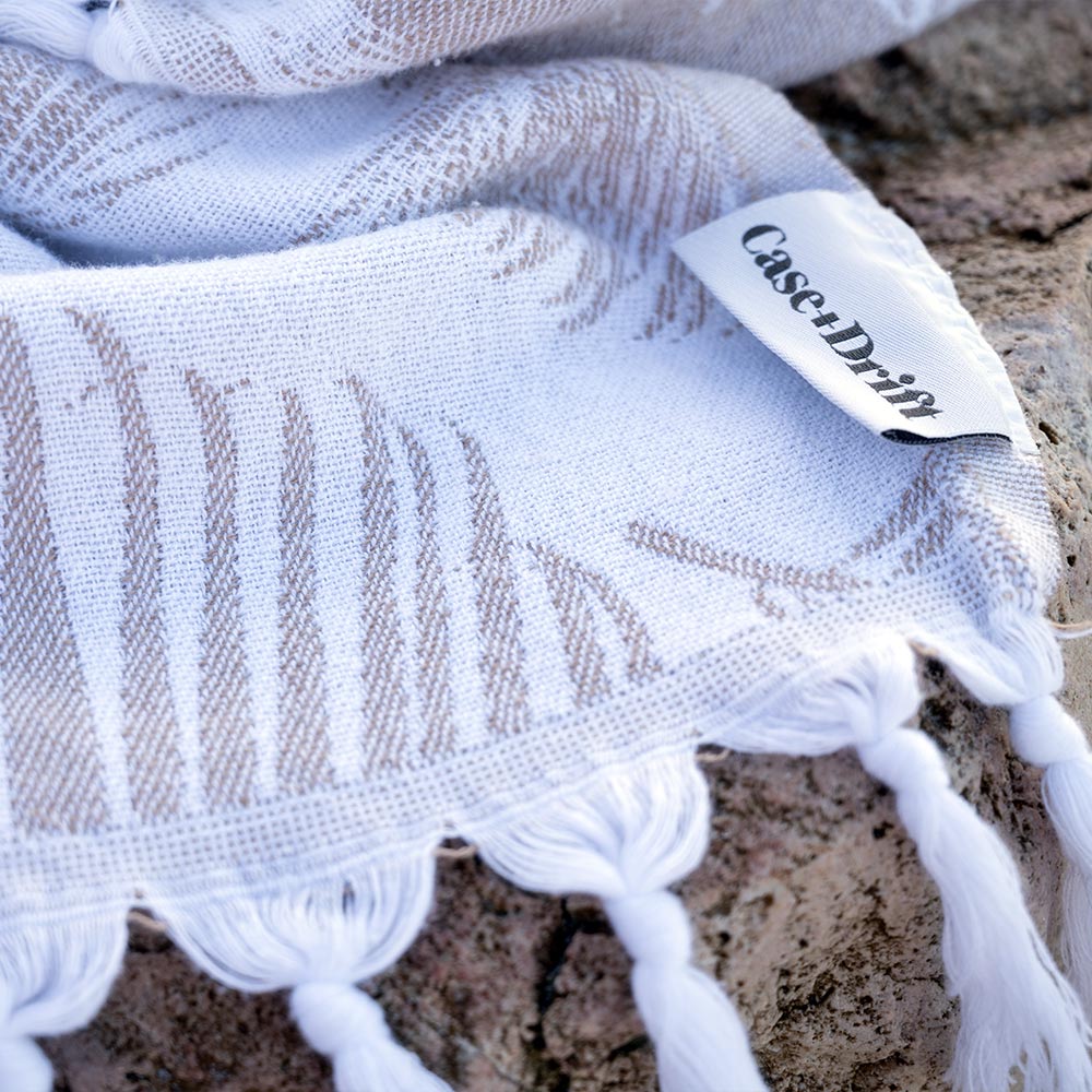 Closeup of the tan Palms Turkish towel by Case+Drift over a rock
