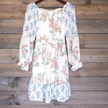 Front view of the Ranee's floral off-shoulder dress hanging on a hanger against a a wood background