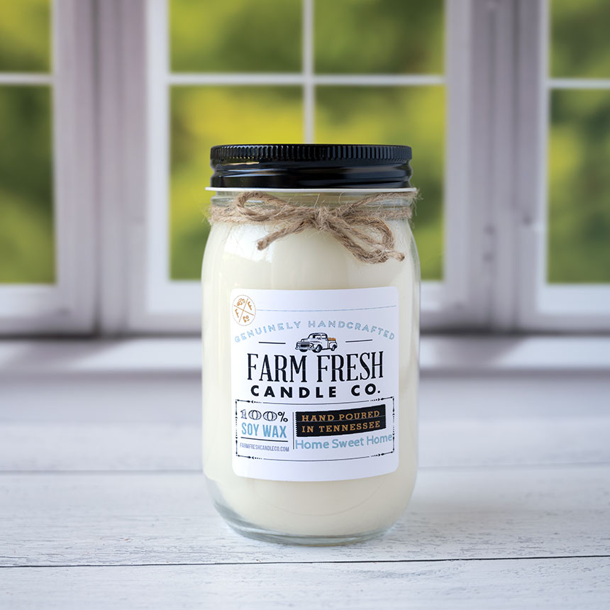 The Home Sweet Home Fall scented soy candle by Farm Fresh Candle Co on a rustic wood top and window with blurred trees