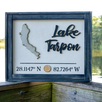 Wood Lake Tarpon Coordinates wood sign by Pine Designs on a railing on a boardwalk along Lake Tarpon