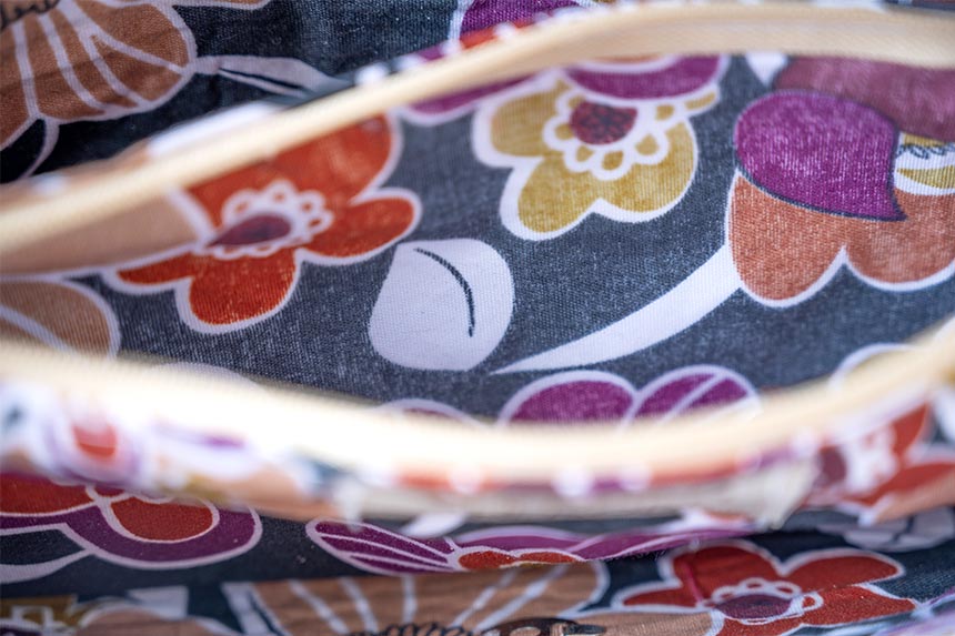 Top closeup view of the women's Tulum flower rattan handbag partial interior and partially opened zipper