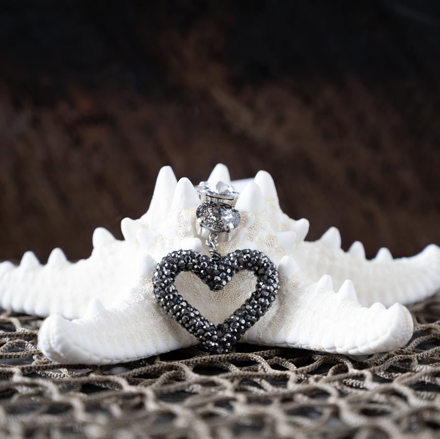 Front view of the crystal heart pendant necklace by Vb & Co laying on a starfish