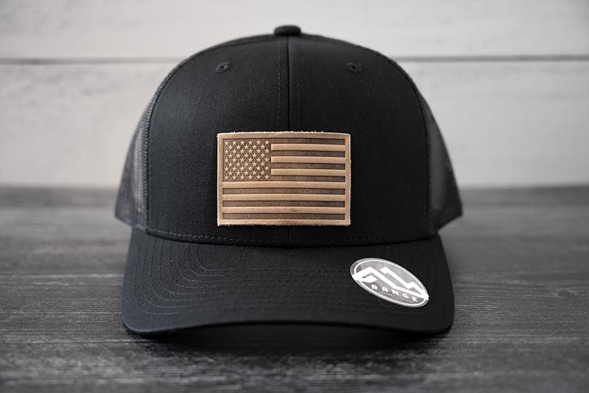 Front view of the RANGE Leather American Leather Patch Hat in black against a wooden backdrop