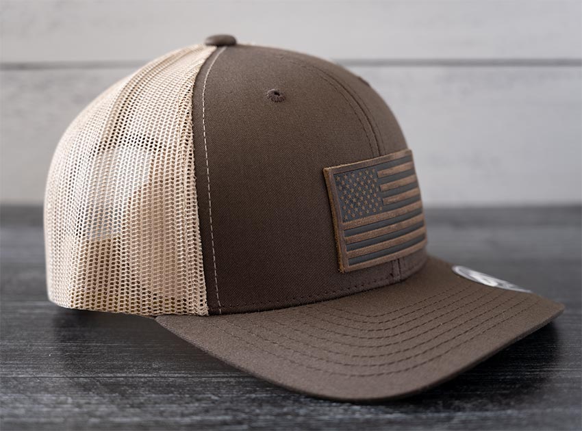 Right angled view of the RANGE Leather American Leather Patch Hat in brown & khaki against a wooden backdrop
