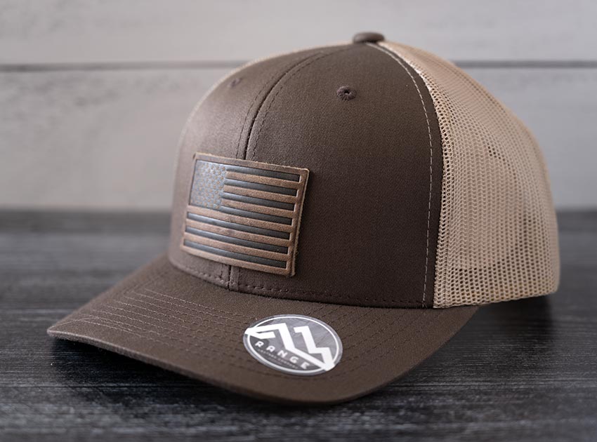 Angled view of the RANGE Leather American Leather Patch Hat in brown & khaki against a wooden backdrop