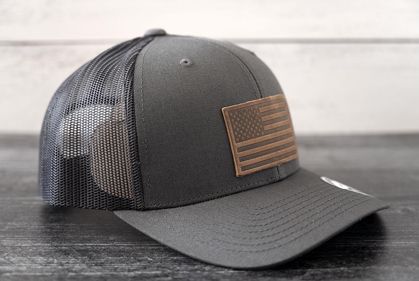 Right Angled view of the RANGE Leather American Leather Patch Hat in charcoal against a wooden backdrop