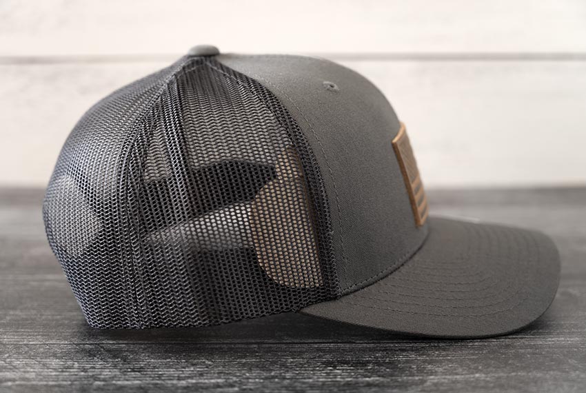 Right Side view of the RANGE Leather American Leather Patch Hat in charcoal against a wooden backdrop