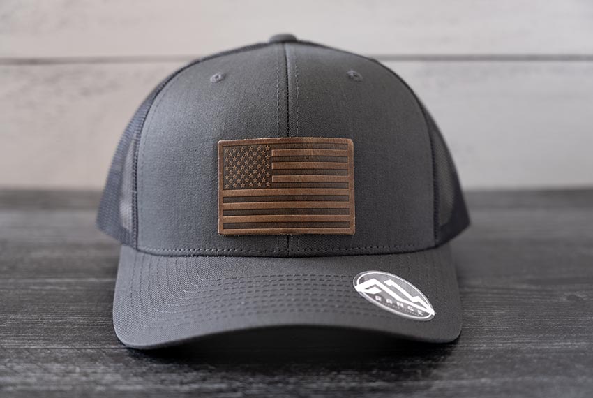 Front view of the RANGE Leather American Leather Patch Hat in charcoal against a wooden backdrop