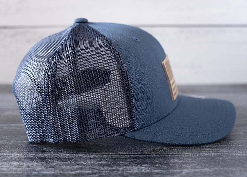Right side view of the RANGE Leather American Leather Patch Hat in navy against a wooden backdrop