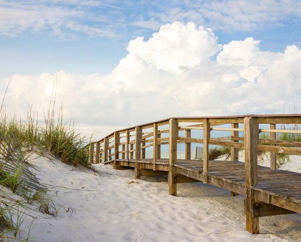 Boardwalk leading to a quiet Florida beach on a blue sky and clouds