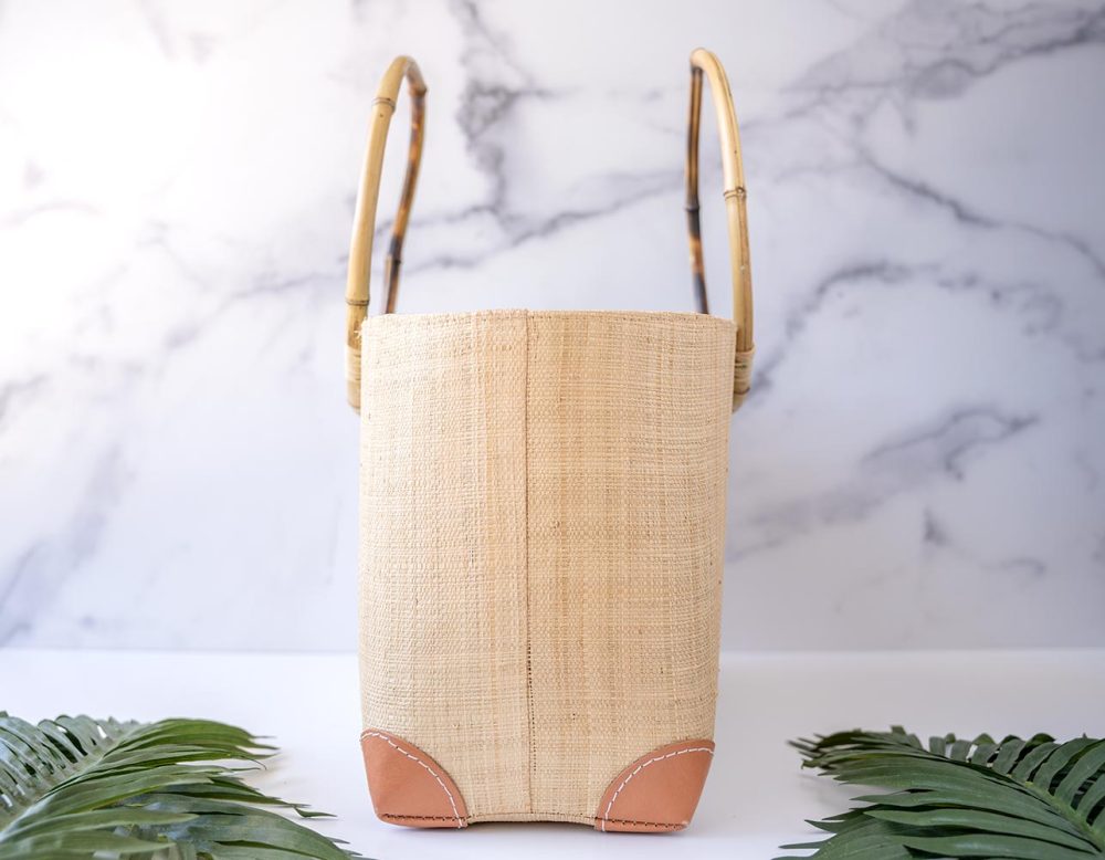 End View of the Shebobo Bebe Straw Bag with Bamboo Handles with Palmn Leaves Laying in Front
