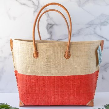 Side View of the Shebobo Monterey Two Tone Straw Bag in Coral with Palm Trees Laying in Front