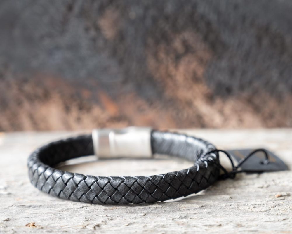Back view of the Steel & Barnett Cornall bracelet in black on and against a rustic wooden backdrop