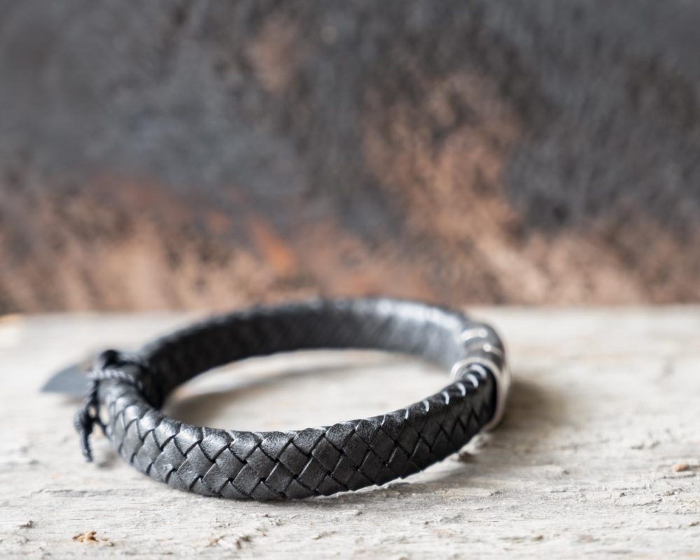 Right view of the Steel & Barnett Cornall bracelet in black on and against a rustic wooden backdrop