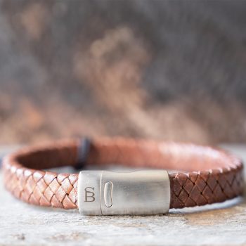 Front view of the Steel & Barnett Cornall bracelet in caramel on and against a rustic wooden backdrop