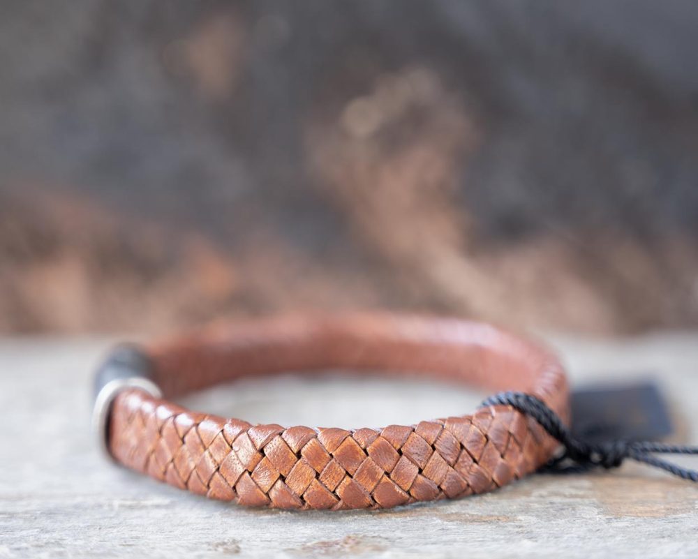 Left side view of the Steel & Barnett Cornall bracelet in caramel on and against a rustic wooden backdrop