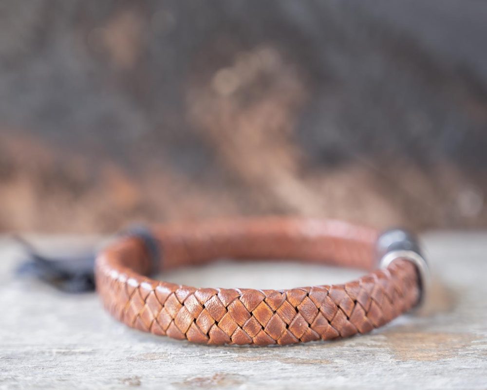 Right side view of the Steel & Barnett Cornall bracelet in caramel on and against a rustic wooden backdrop