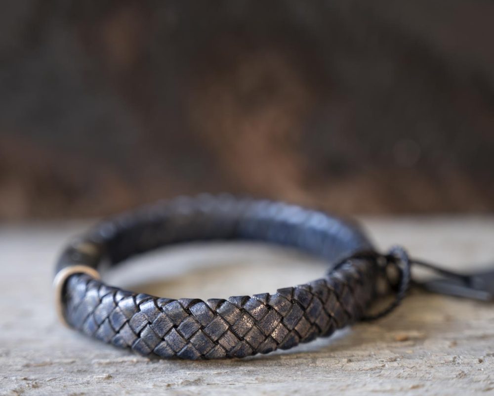Left view of the Steel & Barnett Cornall bracelet in navy on and against a rustic wooden backdrop