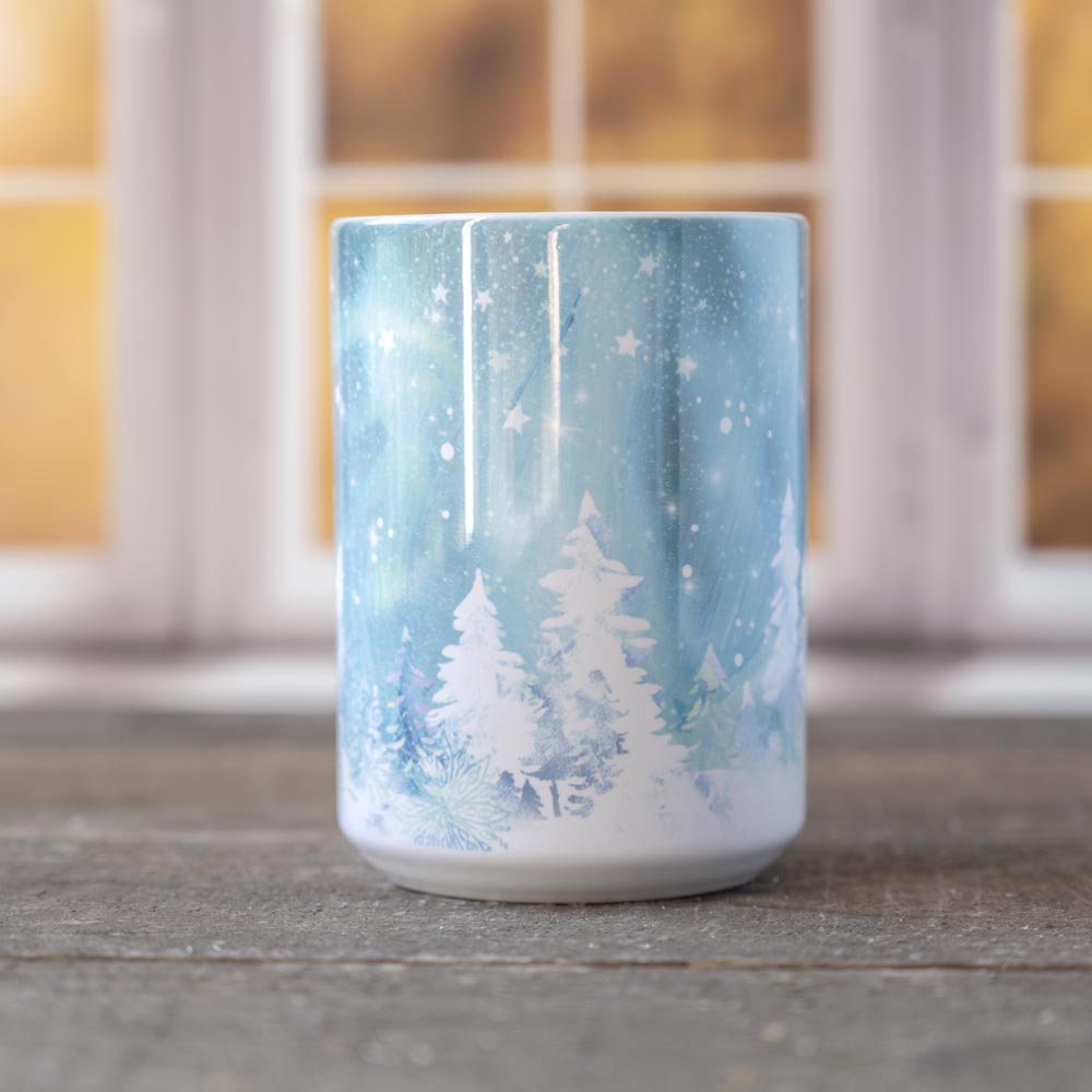 Front view of the Snow & Ice Winter mug against a window backdrop and on top of a wood surface