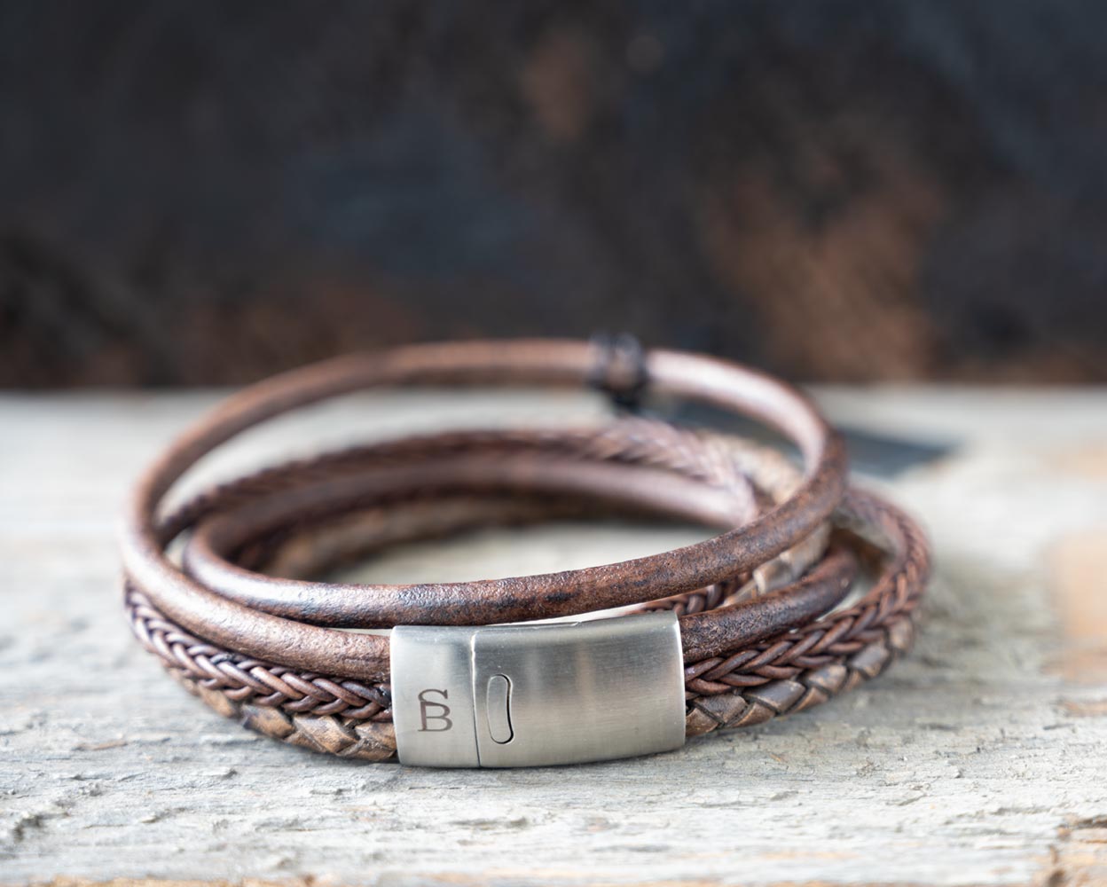 Front view of the brown leather Bonacci bracelet by Steel & Barnett on a rustic piece of wood and backdrop