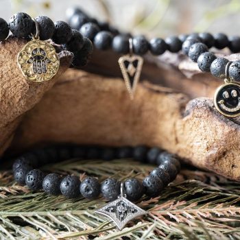 The VB&CO Designs lava oils beads bracelet collection with leaves and wood backdrop