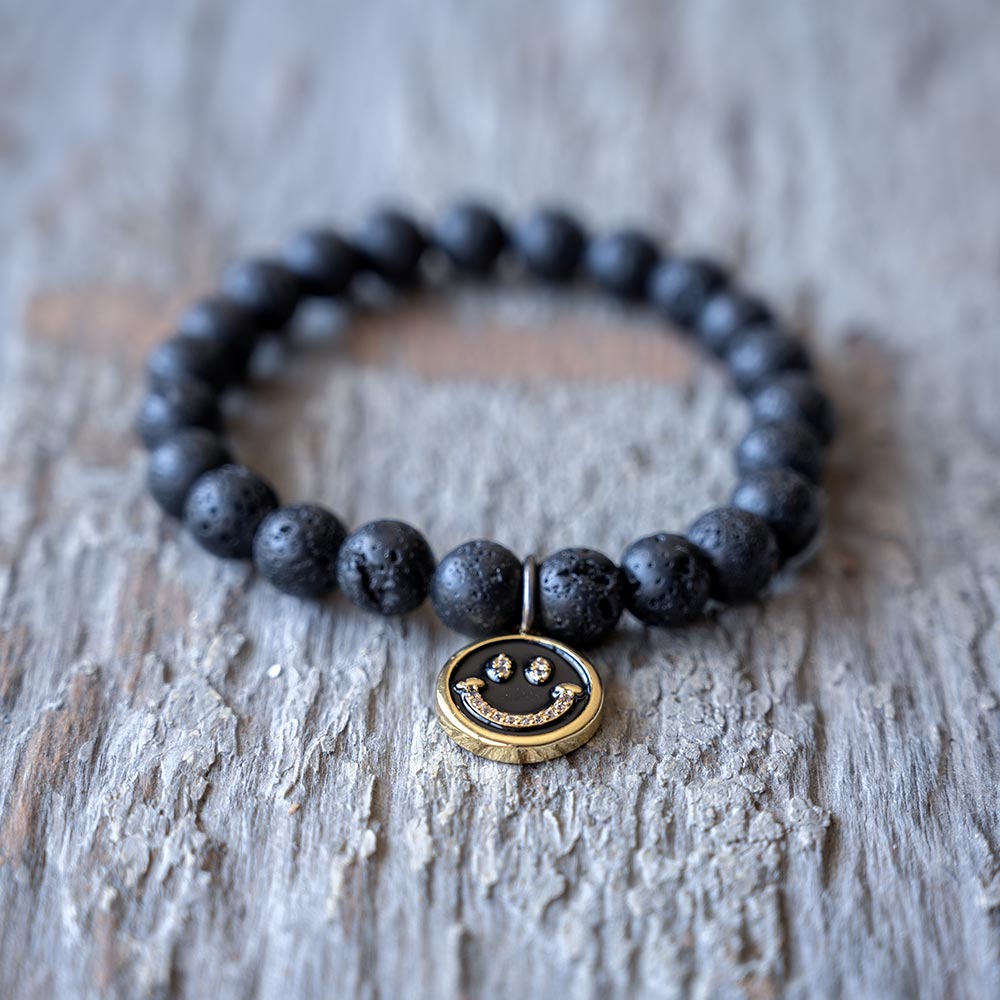 Closeup view of the Smiley Face Oil Lava Beads Bracelet by VB&CO Designs on rustic wood backdrop