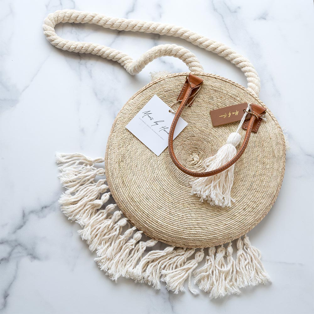 Top view of the Mavis by Herrera Tulum Fringe Crossbody bag with the rope handle extended showing the branded label and tassel