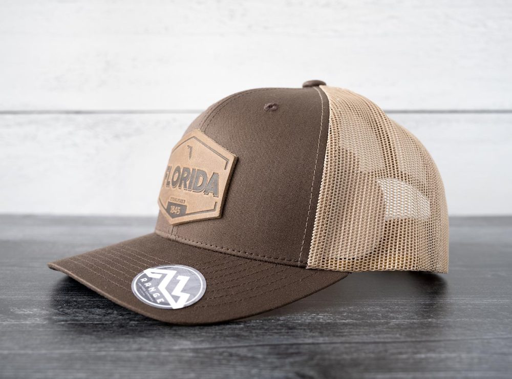Left side view of the RANGE Leather Florida Established hat in brown & khaki on and against a rustic wood backdrop