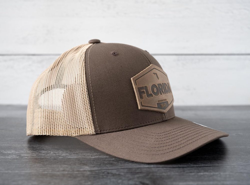 Right side view of the RANGE Leather Florida Established hat in brown & khaki on and against a rustic wood backdrop