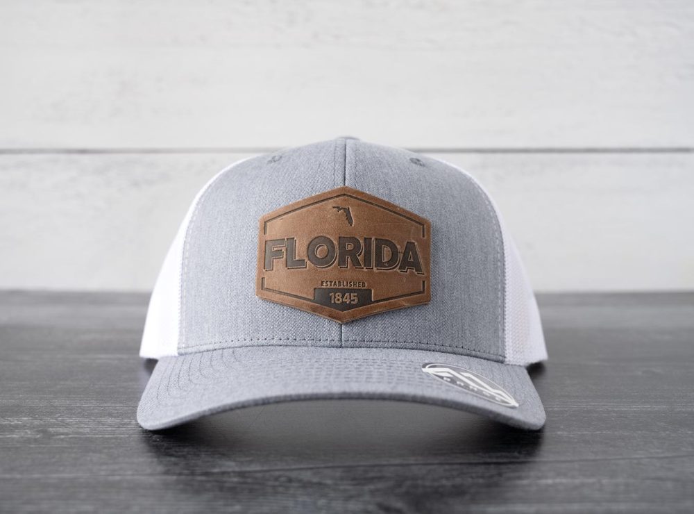 Front view of the RANGE Leather Florida Established hat in heather gray & white on and against a rustic wood backdrop