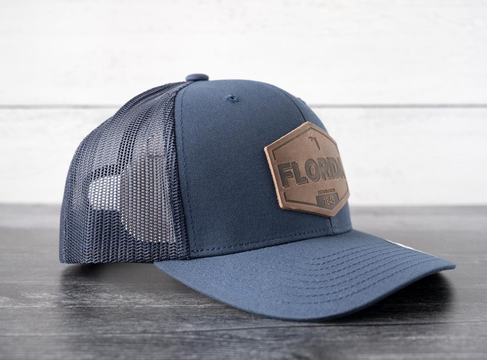 Right side view of the RANGE Leather Florida Established hat in navy on and against a rustic wood backdrop
