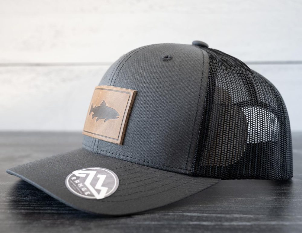 Right angled view of the RANGE Leather Trout hat in the color charcoal against a white and black rustic wood background