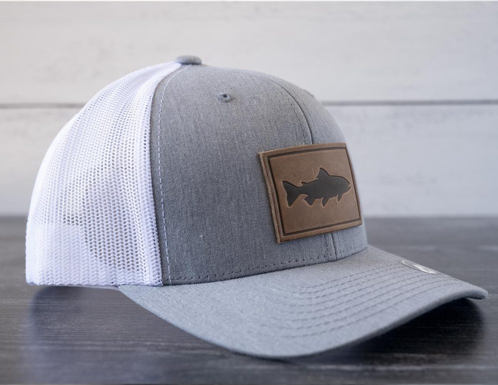 Left angled view of the RANGE Leather Trout hat in the color heather gray & white against a white and black rustic wood background