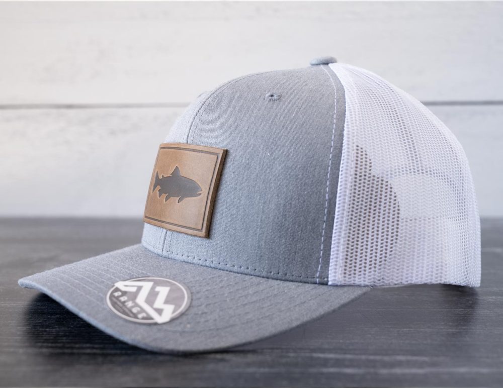 Right angled view of the RANGE Leather Trout hat in the color heather gray & white against a white and black rustic wood background