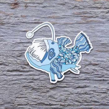 Top view of the Happy Sea Anglerfish sticker on a rustic wood background