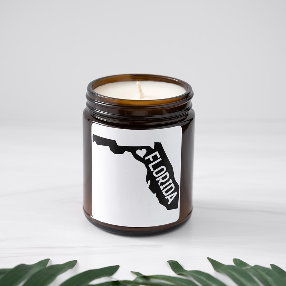 Florida candle by Live Young Candle Company with the top open showing the wick and luxury wax on clean white background with palm leaves in front of the candle